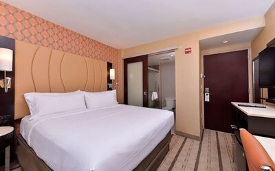 Guest room with king bed, modern décor, and bathroom entrance at Holiday Inn New York City - Times Square By IHG.