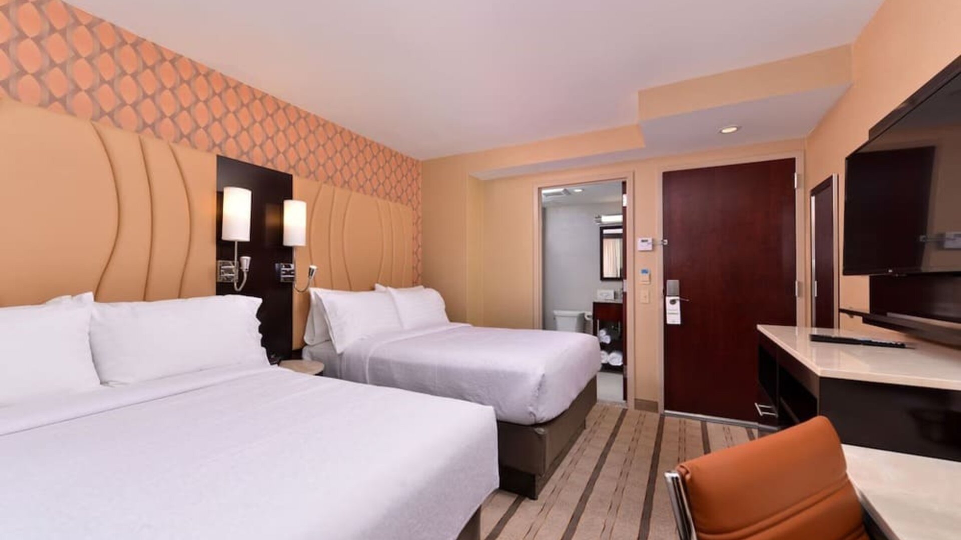 Guest room with two double beds, modern furnishings, and workspace area at Holiday Inn New York City - Times Square By IHG.