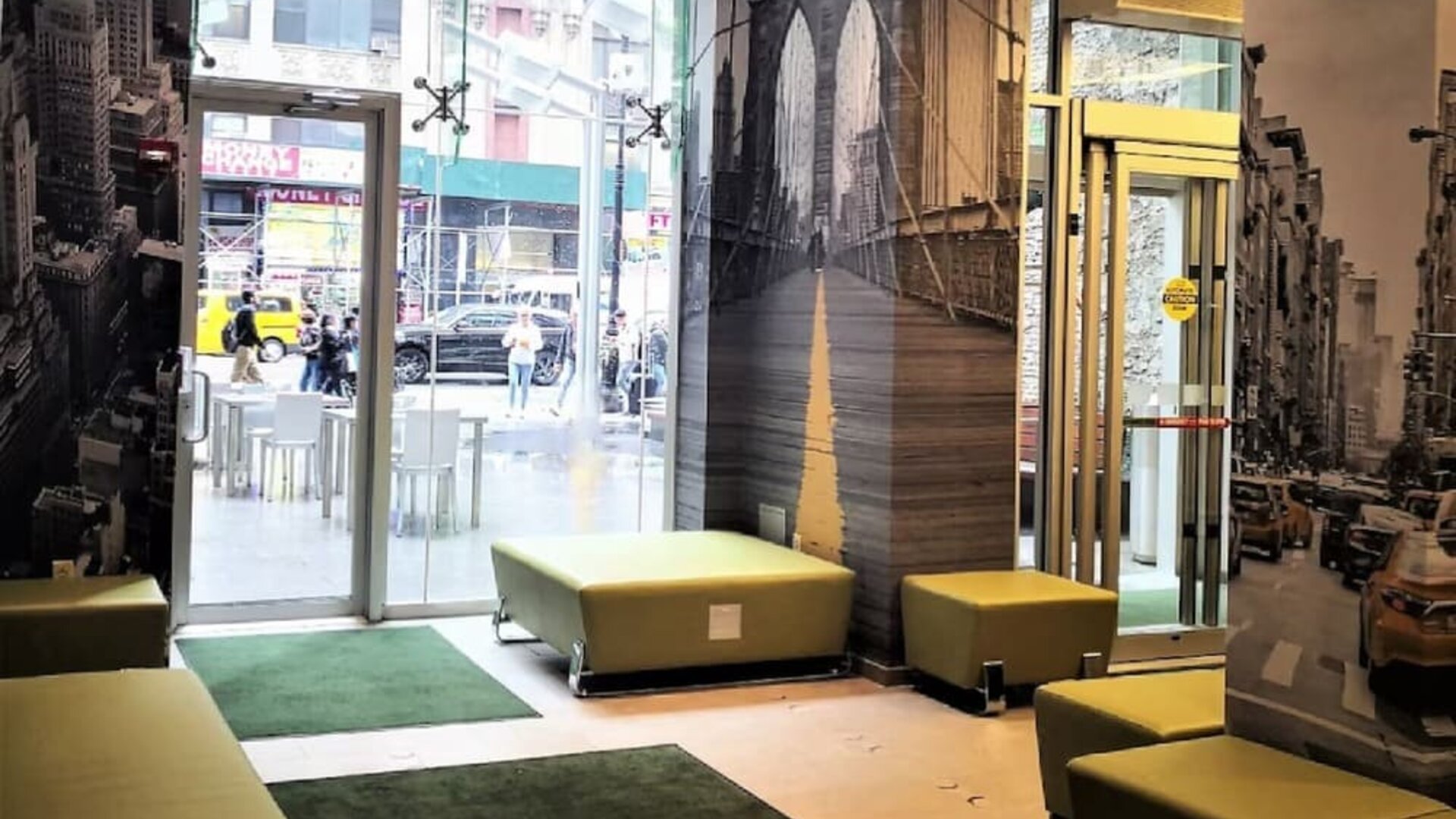 Lobby seating area with modern décor, wall art, and glass entrance at Holiday Inn New York City - Times Square By IHG.