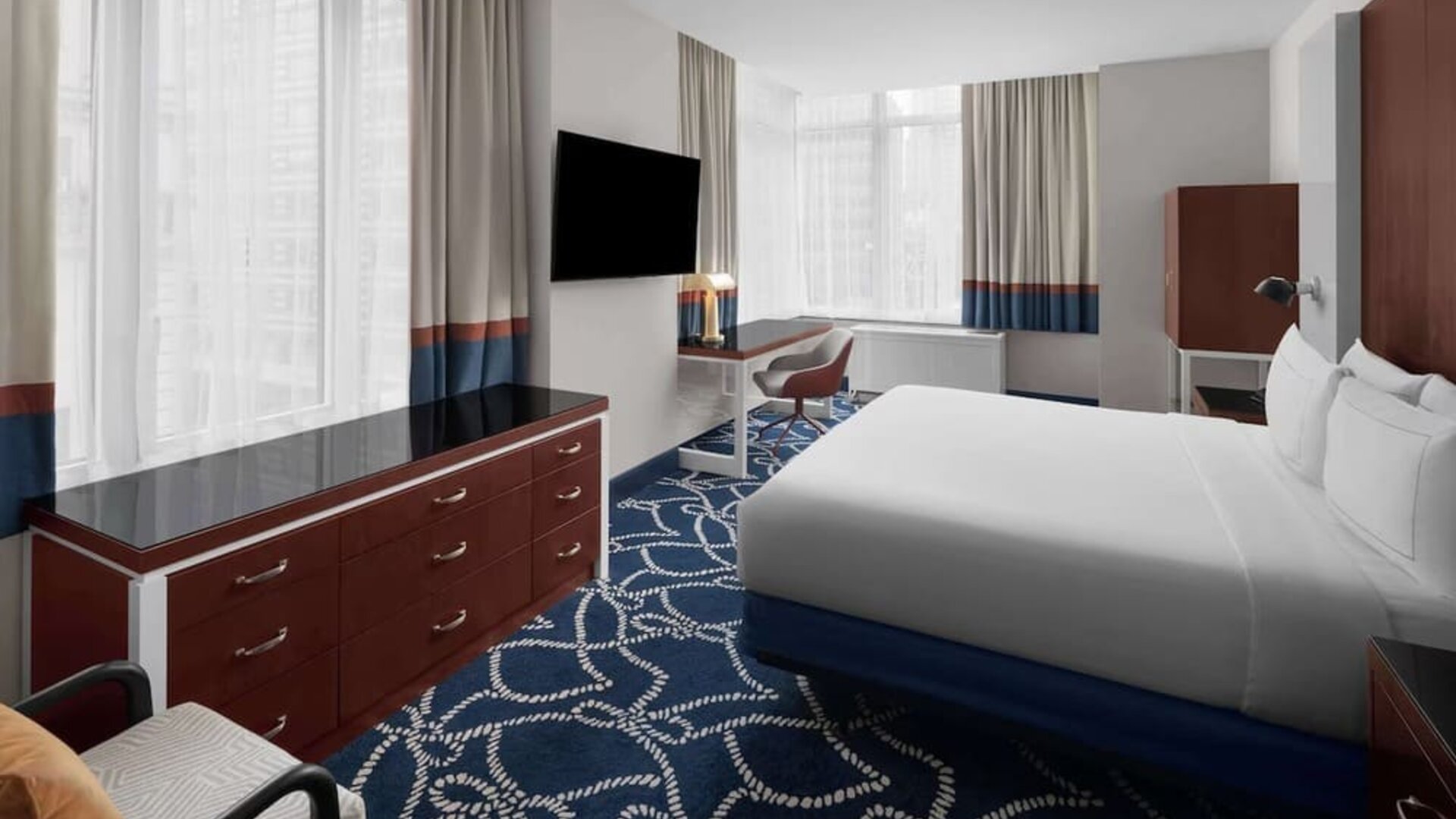 Guest room with king bed, workspace desk, chair, and large windows at Hilton Brooklyn New York.
