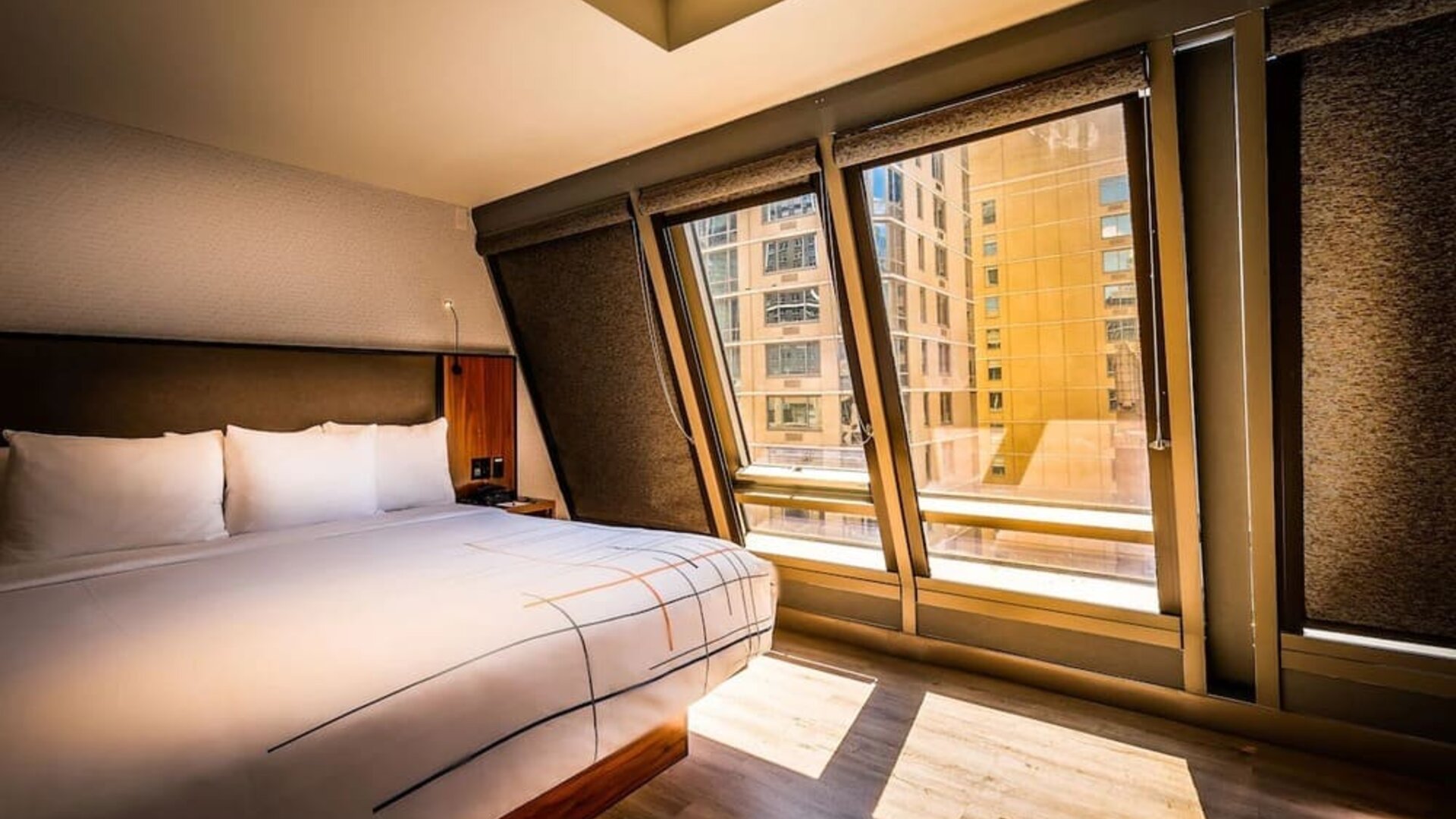Guest room with king bed and large angled windows providing natural light and city views at La Quinta Times Square South.