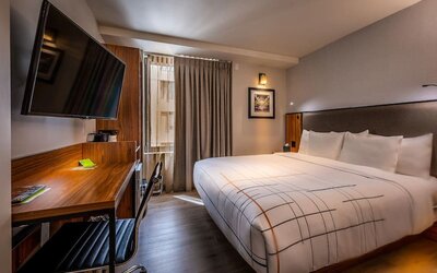 Guest room with king bed, workspace desk, chair, and wall-mounted TV at La Quinta Times Square South.