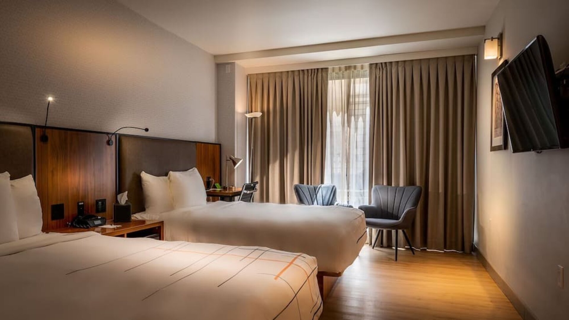 Guest room with two double beds, seating area, and large window with natural light at La Quinta Times Square South.