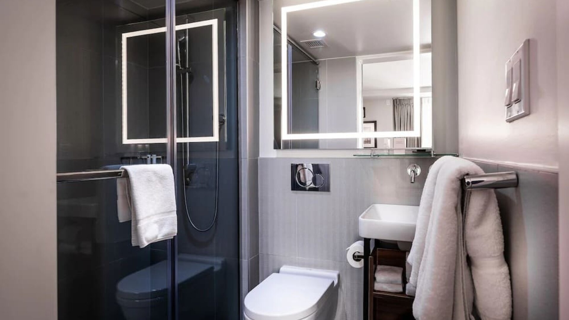 Bathroom with glass-enclosed shower, sink, mirror, and towels at La Quinta Times Square South.