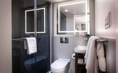 Bathroom with glass-enclosed shower, sink, mirror, and towels at La Quinta Times Square South.