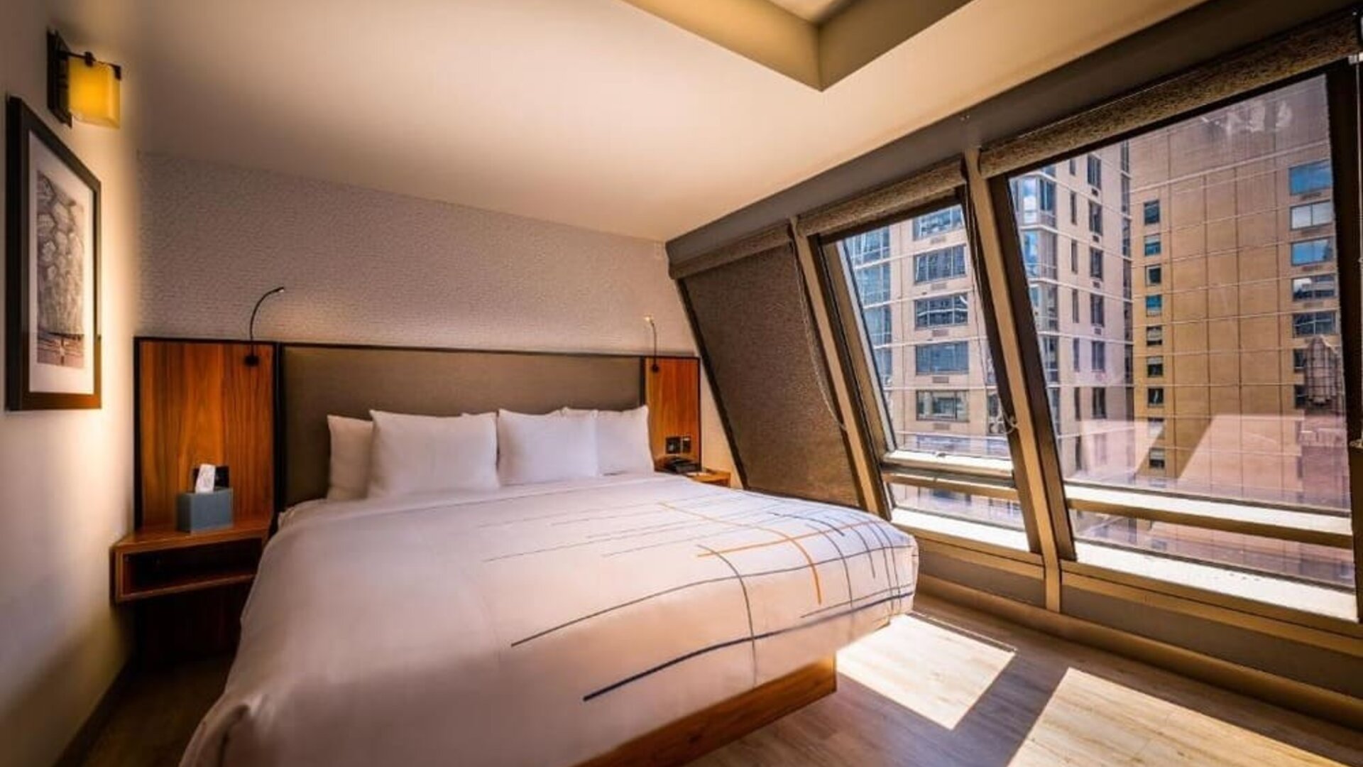 Guest room with king bed and angled floor-to-ceiling windows offering city views at La Quinta Times Square South.