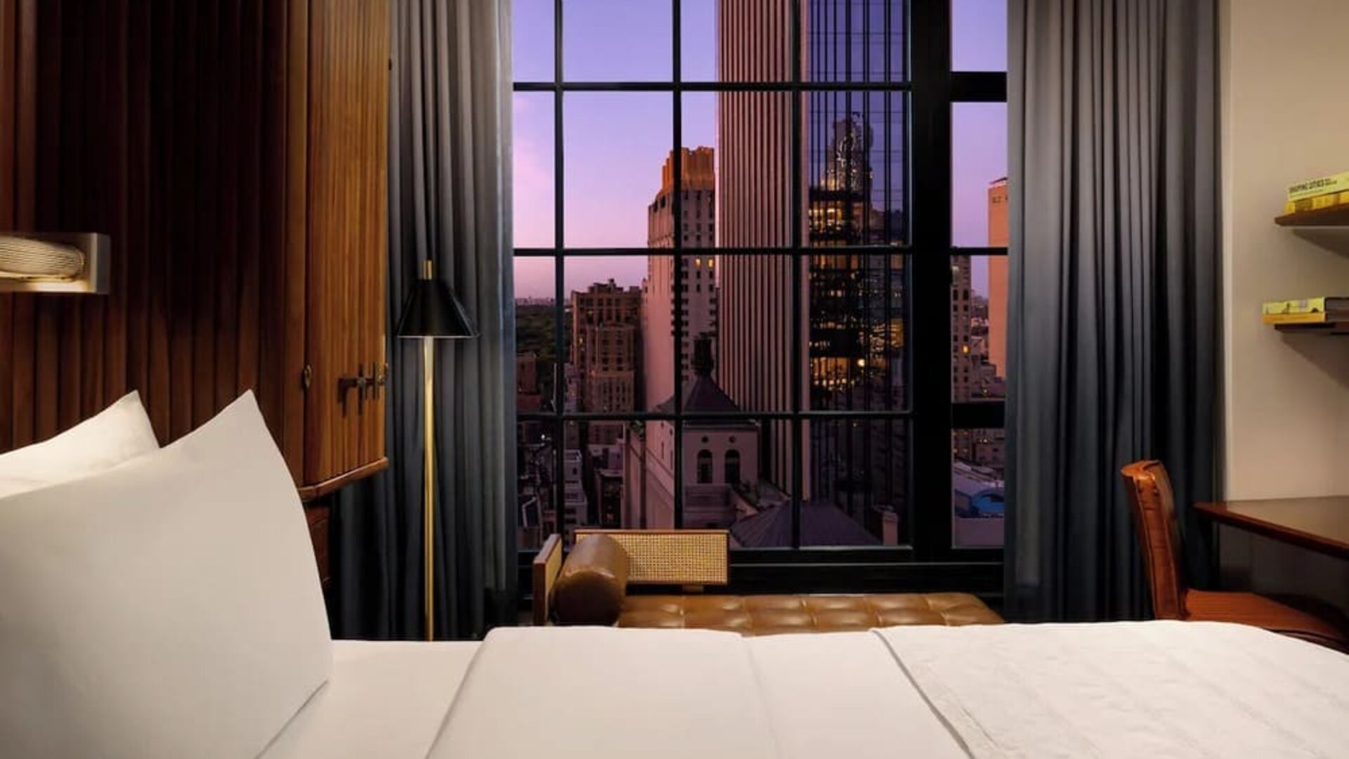 Guest room with king bed and large window showcasing city skyline views at Le Méridien New York, Central Park.