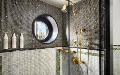 Bathroom with walk-in shower, mosaic tiles, and gold fixtures at Le Méridien New York, Central Park.