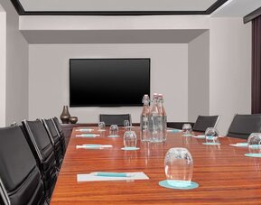 Meeting room with conference table, chairs, and presentation screen at Le Méridien New York, Central Park.