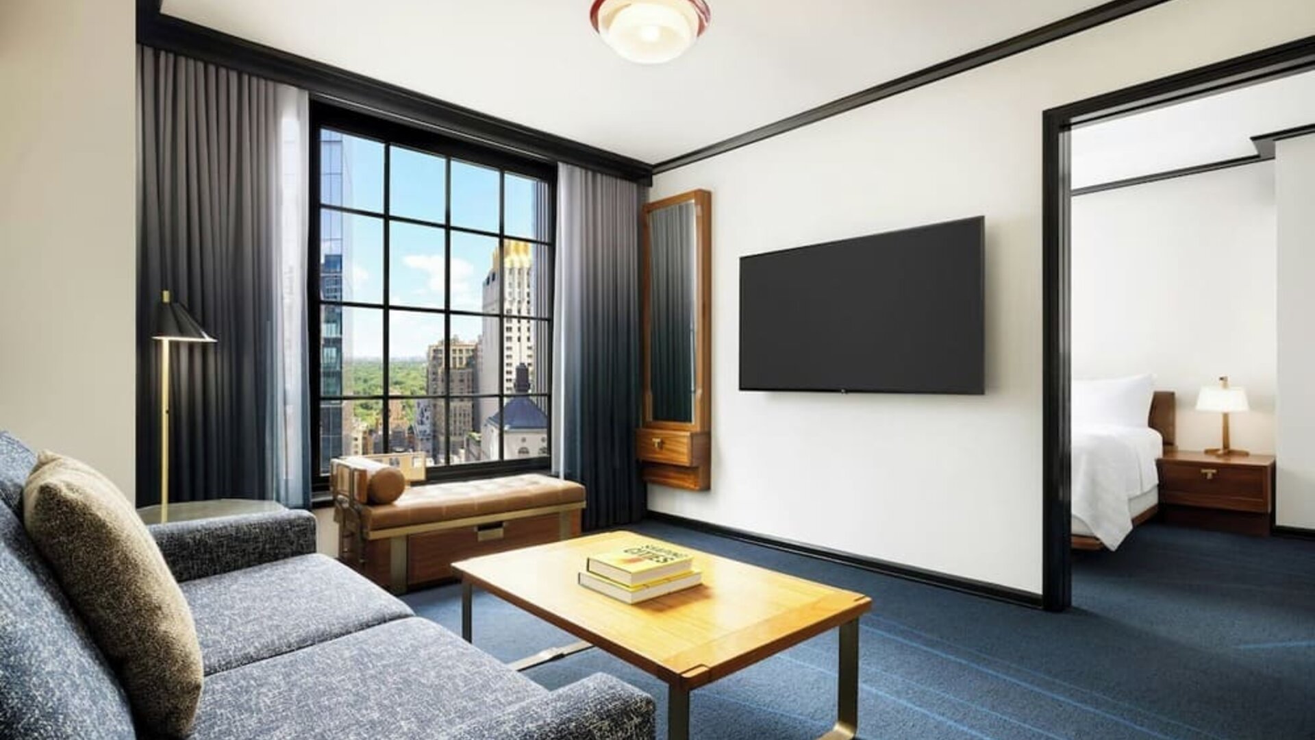 Living area with sofa, coffee table, and connected bedroom space at Le Méridien New York, Central Park.