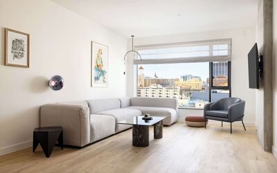 Living area with sofa, armchair, and city views through large windows at Timbri Hotel San Francisco, Curio Collection By Hilton.