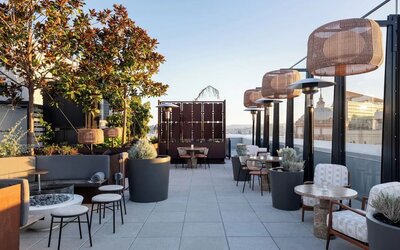 Outdoor terrace dining area with plants, seating, and city skyline views at Timbri Hotel San Francisco, Curio Collection By Hilton