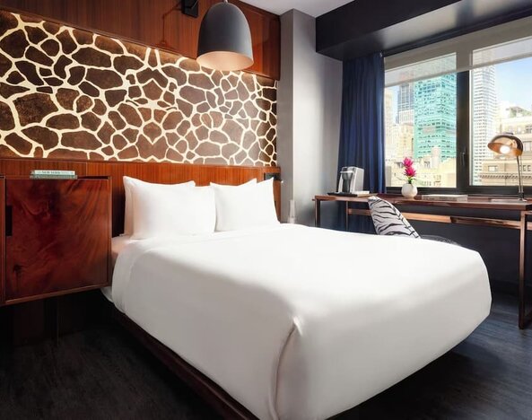 Stylish guest room with king bed, desk workspace, city views, and decorative feature wall at Hotel Hendricks.