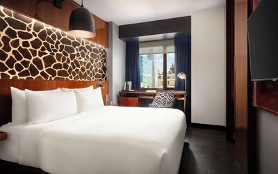 King room with modern décor, wall-mounted TV, workspace, and large window at Hotel Hendricks.