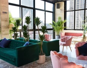 Lobby lounge with plush seating, large windows, and indoor plants at Hotel Hendricks.