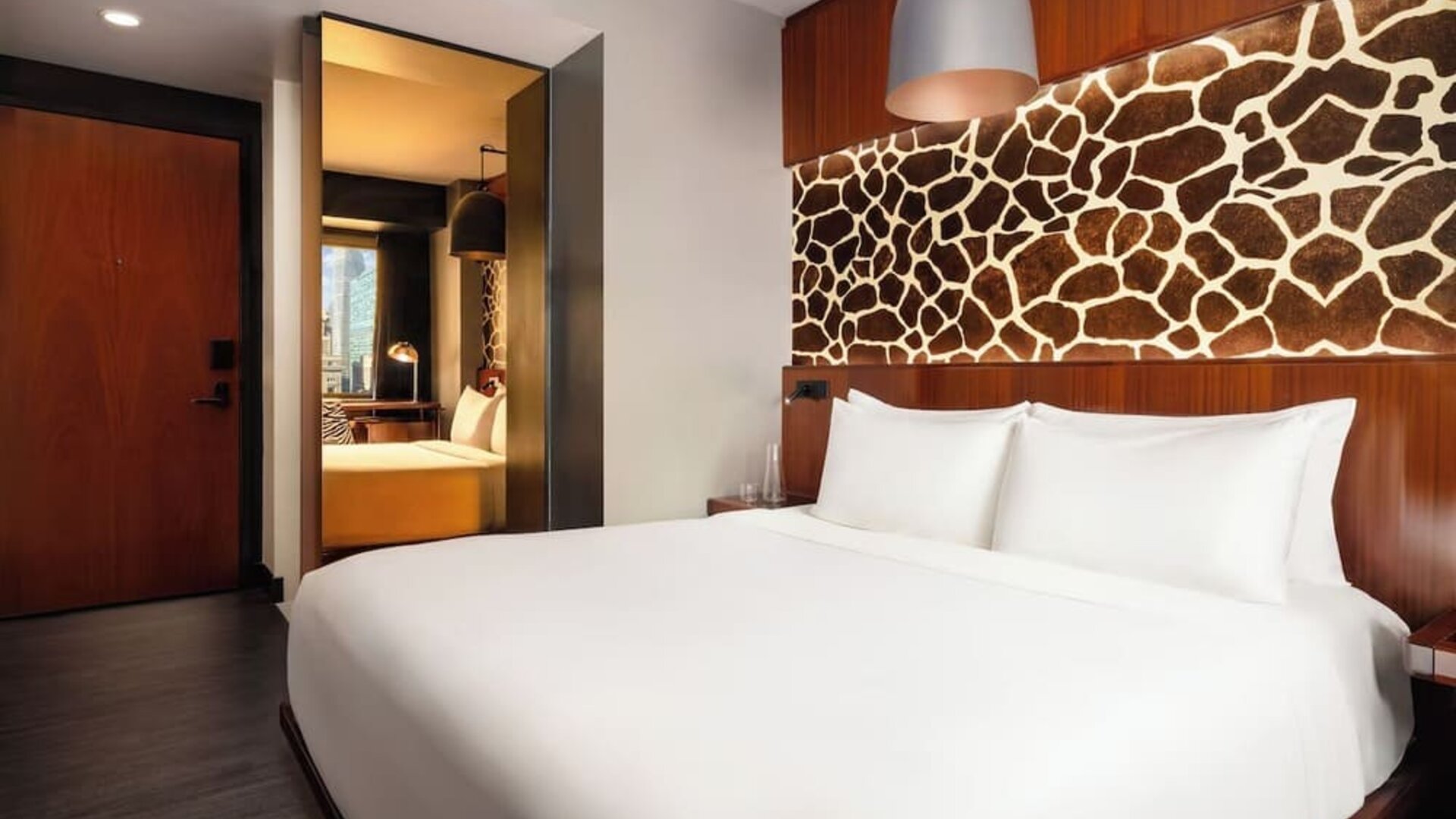 Guest room with large bed, decorative wall panel, and sleek interior design at Hotel Hendricks.