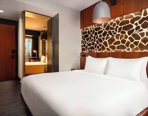 Guest room with large bed, decorative wall panel, and sleek interior design at Hotel Hendricks.