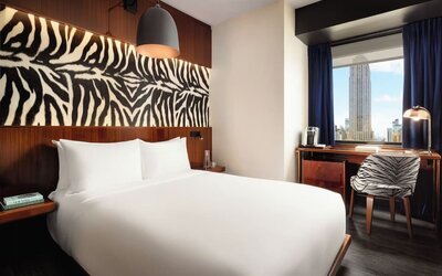 Bright room with natural light, workspace, and city skyline views at Hotel Hendricks.