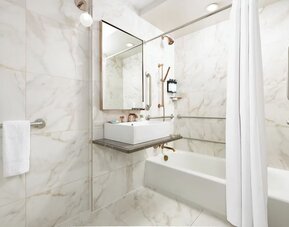 Bathroom with bathtub, marble finishes, grab rails, and contemporary sink area at Hotel Hendricks.