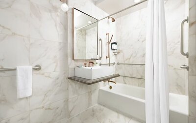 Bathroom with bathtub, marble finishes, grab rails, and contemporary sink area at Hotel Hendricks.