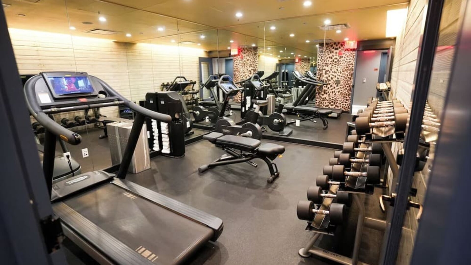 Fitness center with treadmills, weights, and mirrored walls at Hotel Hendricks.