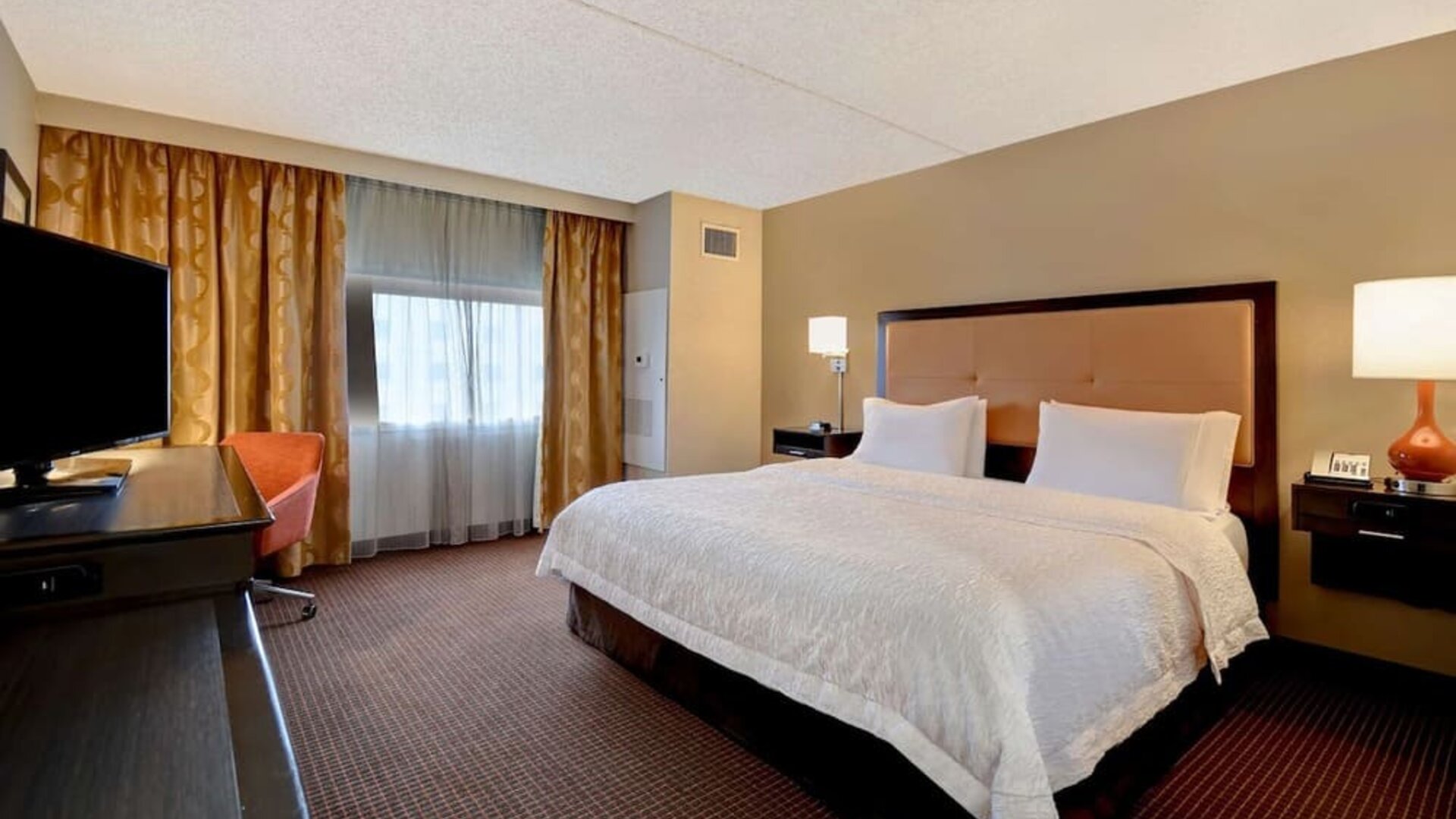 Day use room with TV, work desk, and natural light at Hampton Inn NY-JFK.