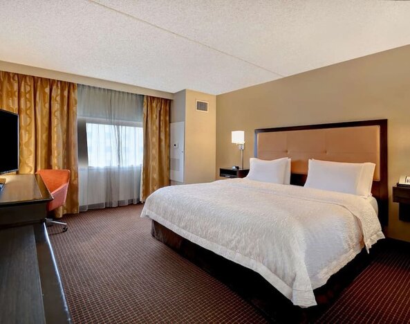 Day use room with TV, work desk, and natural light at Hampton Inn NY-JFK.