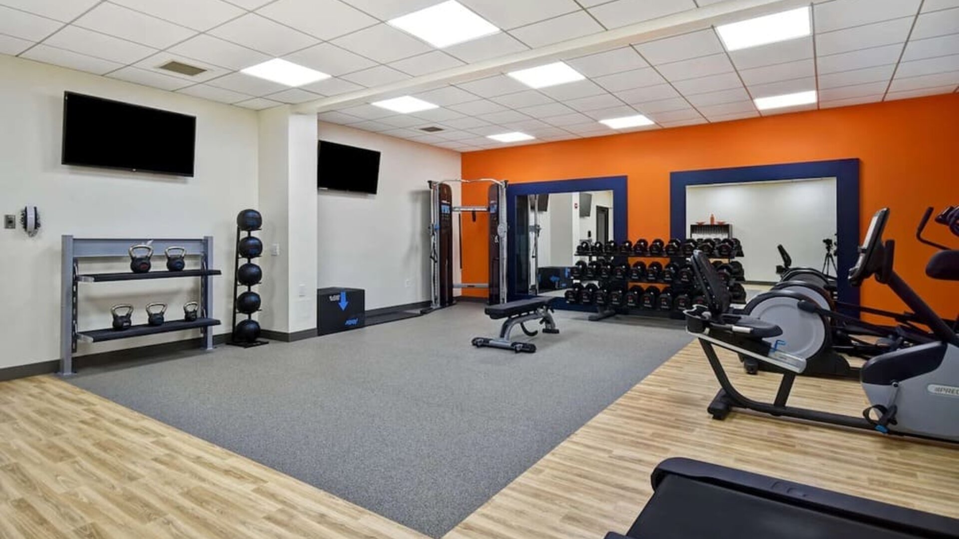 Fitness center with treadmills and weights at Hampton Inn NY-JFK.