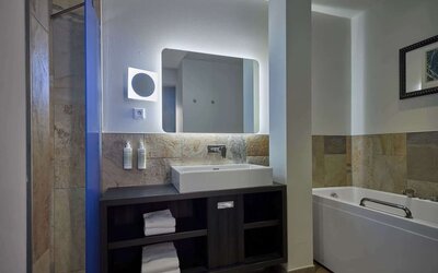 Guest bathroom with bath and shower at Haven Hotel Rotterdam.