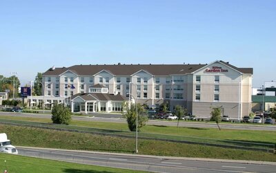 Hotel exterior with green garden at Hilton Garden Inn Montreal Airport.