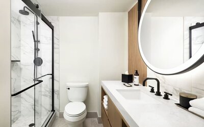 Modern bathroom with glass-enclosed shower, marble walls, and vanity at Hyatt Regency Times Square.