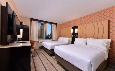 Guest room with two double beds, modern furnishings, and city view window at Holiday Inn New York City - Times Square By IHG.