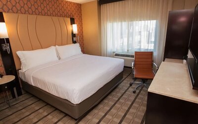 Guest room with king bed, workspace desk, chair, and window with natural light at Holiday Inn New York City - Times Square By IHG.