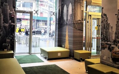 Lobby seating area with modern décor, wall art, and glass entrance at Holiday Inn New York City - Times Square By IHG.
