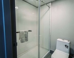 Bathroom with glass-enclosed shower, tiled walls, and modern fixtures at Wyndham Garden Williamsburg Busch Gardens Area.