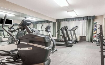 Fitness center with cardio machines, free weights, and mirrored wall at Wyndham Garden Williamsburg Busch Gardens Area.
