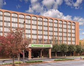 Hotel exterior with Wyndham Garden signage, covered entrance, and parking area at Wyndham Garden Williamsburg Busch Gardens Area.