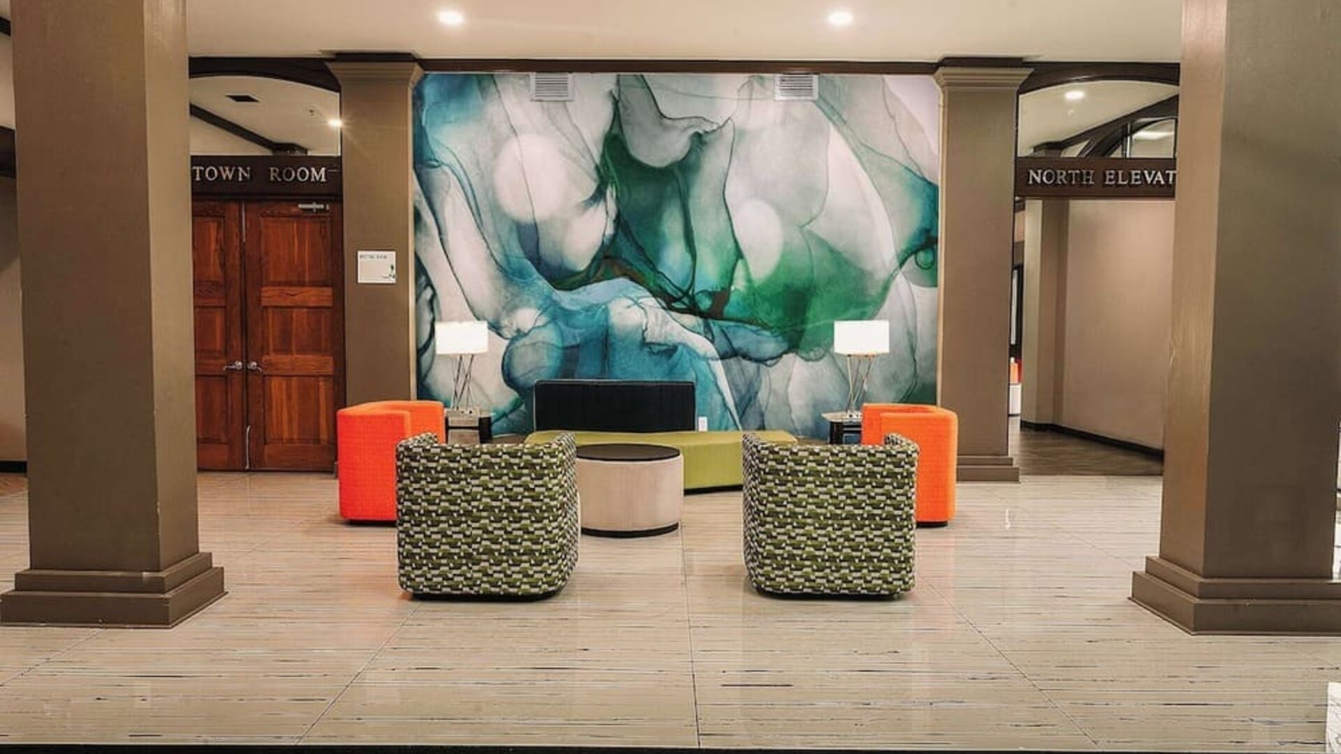 Lobby seating area with modern chairs, decorative wall art, and open layout at Wyndham Garden Williamsburg Busch Gardens Area.