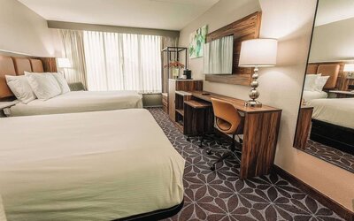 Two-bed guest room with desk, mirror, and contemporary design at Wyndham Garden Williamsburg Busch Gardens Area.