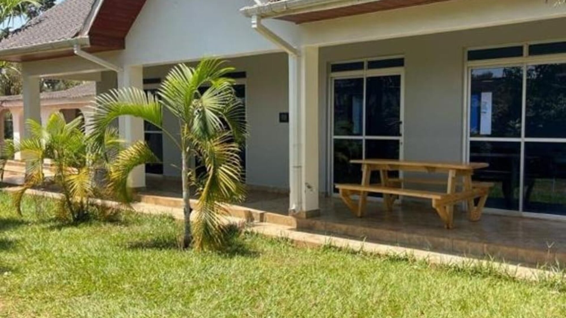 Close-up exterior of a lodge building with tiled roof, covered patio, and outdoor seating area at Sega Lodge.
