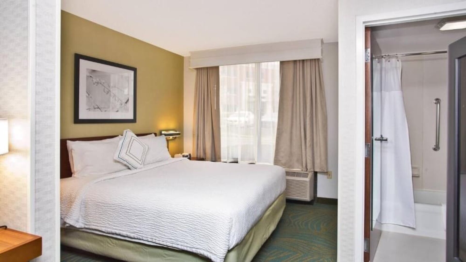 Guest room with king bed, white bedding, window with curtains and an armchair at Marriott SpringHill Suites Naperville/Warrenville.