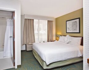 King guest room with white bedding, work desk, window seating area, and accessible bathroom at Marriott SpringHill Suites Naperville/Warrenville.