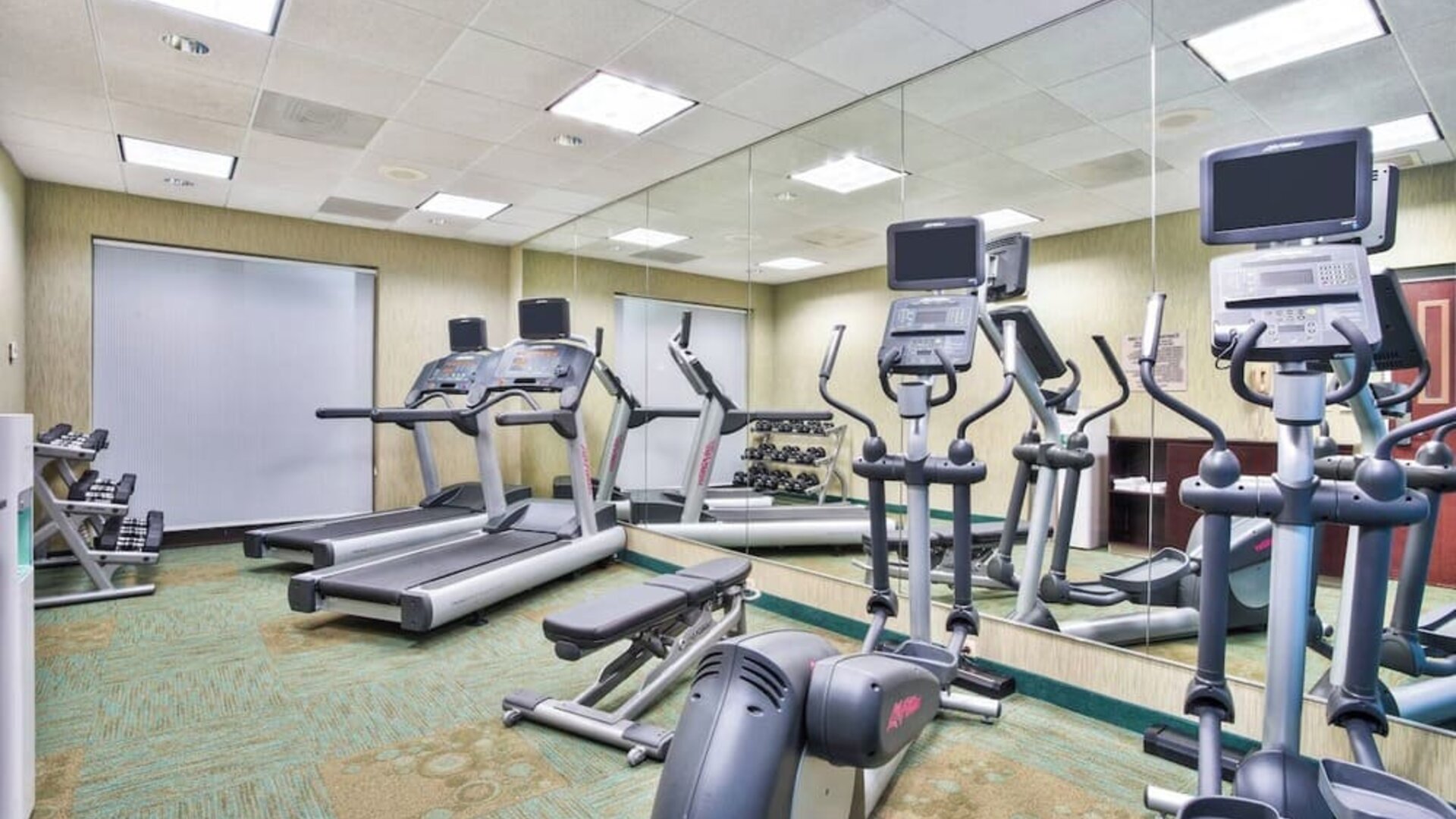 Fitness center at Marriott SpringHill Suites Naperville/Warrenville with treadmills, ellipticals, and mirrored wall.