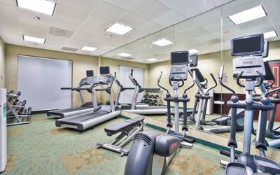 Fitness center at Marriott SpringHill Suites Naperville/Warrenville with treadmills, ellipticals, and mirrored wall.