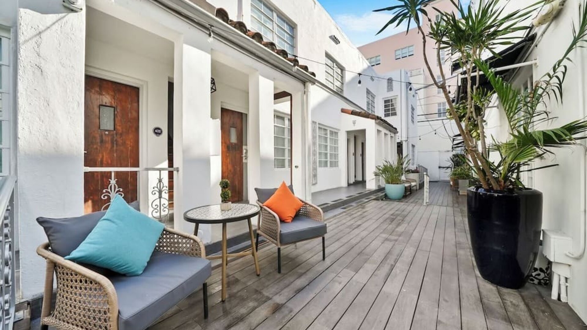 Outdoor courtyard with white buildings, wooden deck, seating areas, and potted plants at Chesterfield Hotel & Suites.