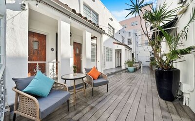 Outdoor courtyard with white buildings, wooden deck, seating areas, and potted plants at Chesterfield Hotel & Suites.