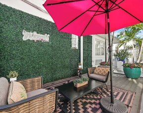 Cozy terrace with cushioned seating, patterned rug, green wall backdrop, and large umbrella at Chesterfield Hotel & Suites.