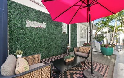 Cozy terrace with cushioned seating, patterned rug, green wall backdrop, and large umbrella at Chesterfield Hotel & Suites.