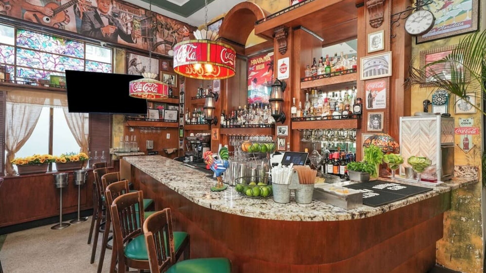 Retro-style bar with wood finishes, marble counter, vintage posters, and stocked shelves of bottles at Hotel Chelsea, A South Beach Group Hotel.