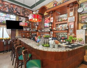 Retro-style bar with wood finishes, marble counter, vintage posters, and stocked shelves of bottles at Hotel Chelsea, A South Beach Group Hotel.
